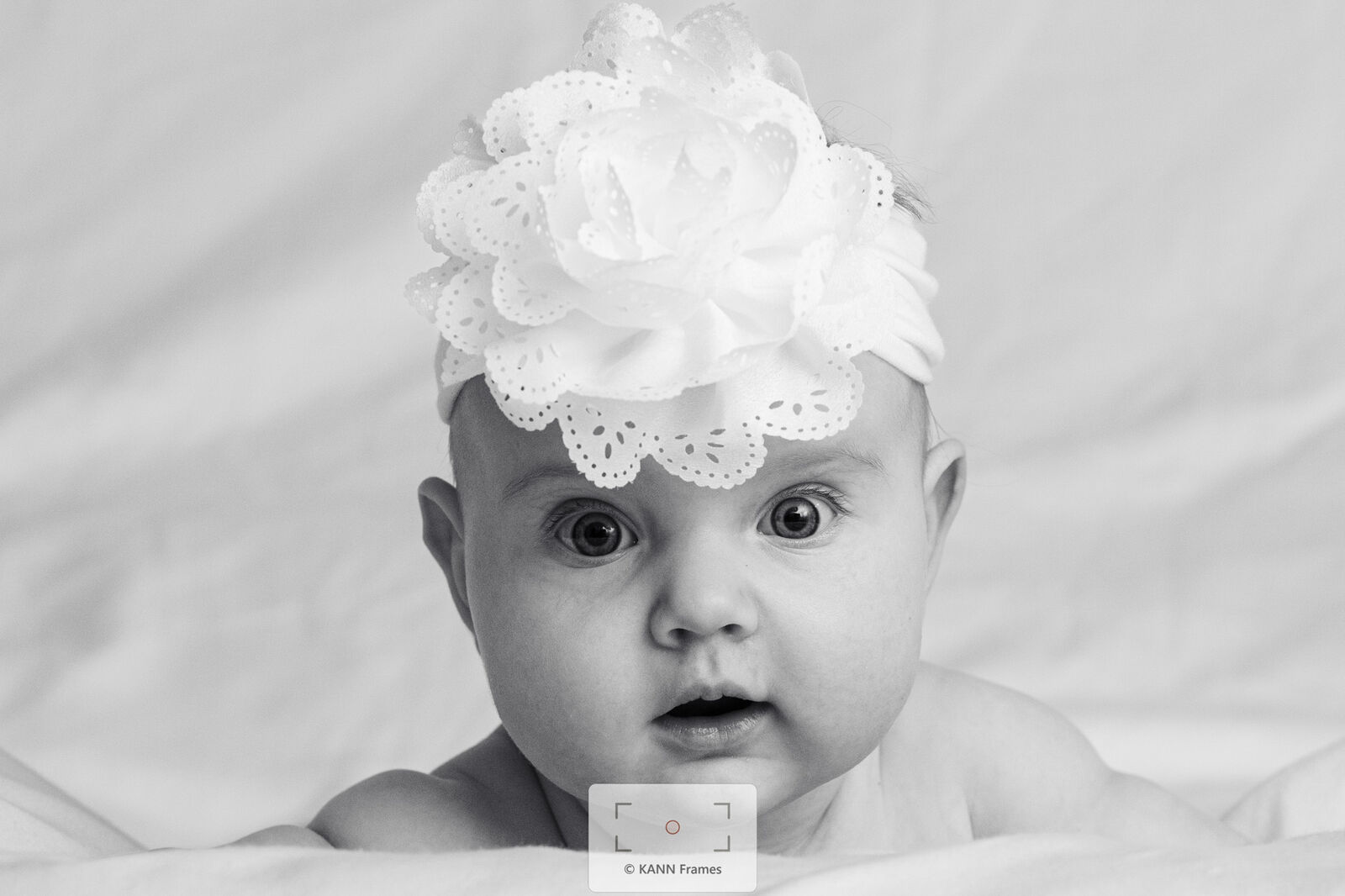 Black and white portrait of a baby wearing a lace flower headband